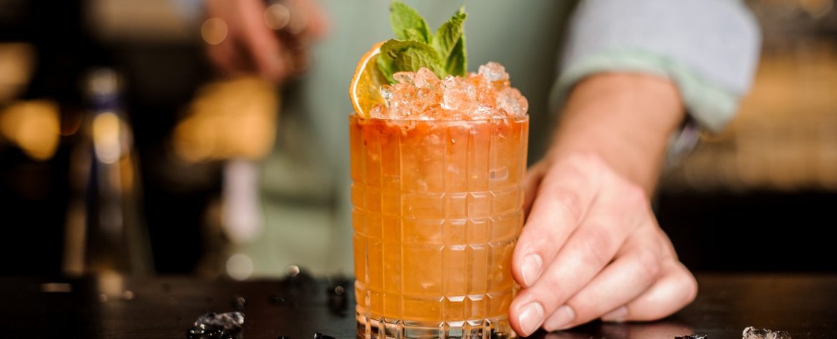 a decorated cocktail with mint and an orange slice in a glass on the bartop of a state street santa barbara bar.